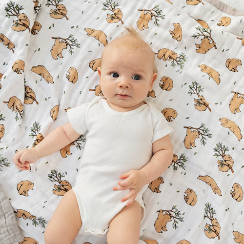 Baby laying awake on cotton muslin blanket with bear pattern