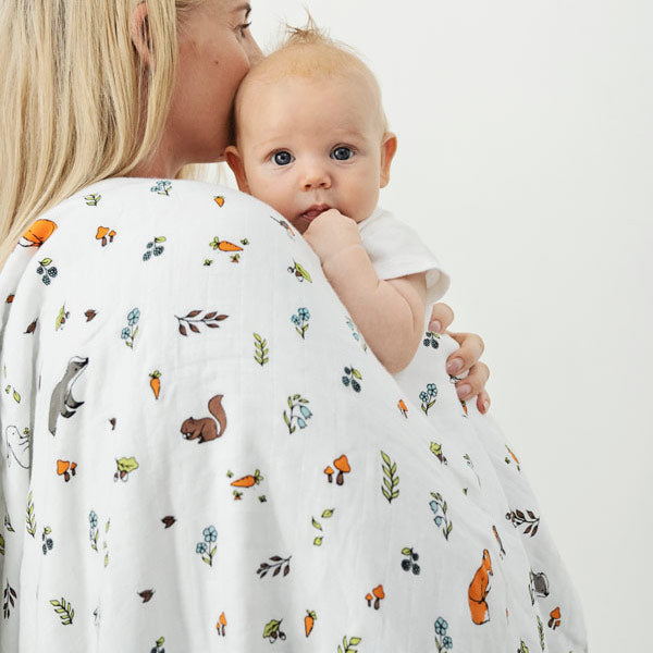 Mother holding baby covered with muslin blanket
