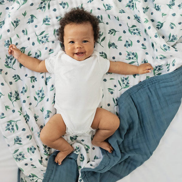 Laughing baby on organic cotton muslin quilt with blueberry pattern