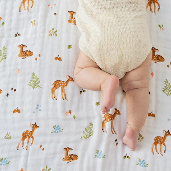 Baby laying awake on cotton muslin blanket with fawn pattern