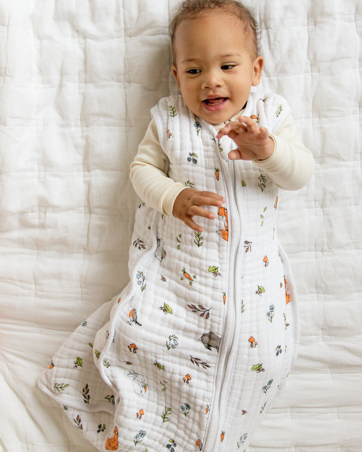 Baby wearing organic cotton muslin baby sleeping bag 1.5 tog with woodland pattern